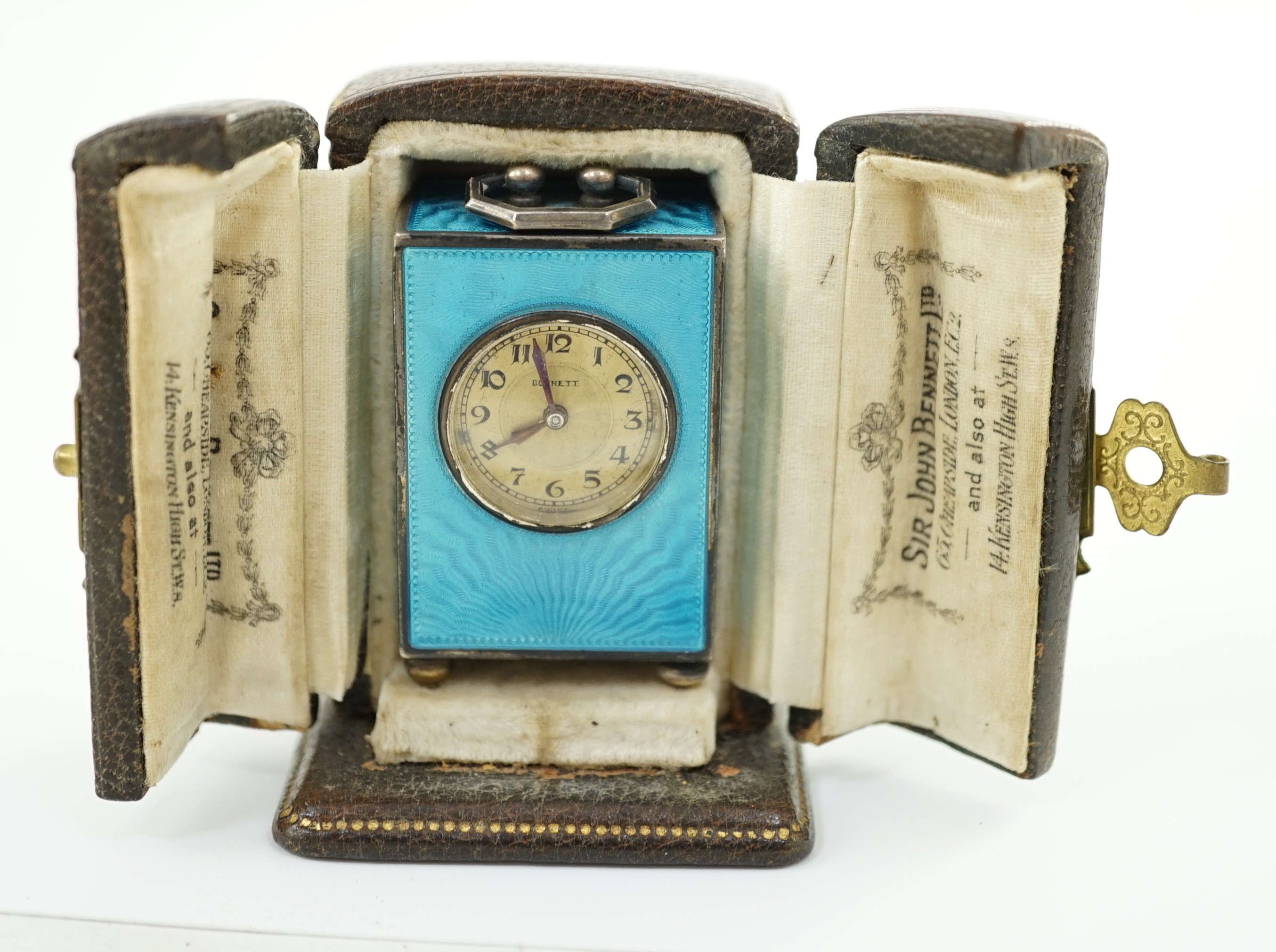 A George V Swiss blue enamel and silver cased miniature carriage timepiece, import marks for Arthur George Rendell, London, 1924, 43mm, on bun feet, in gilt tooled leather carrying case